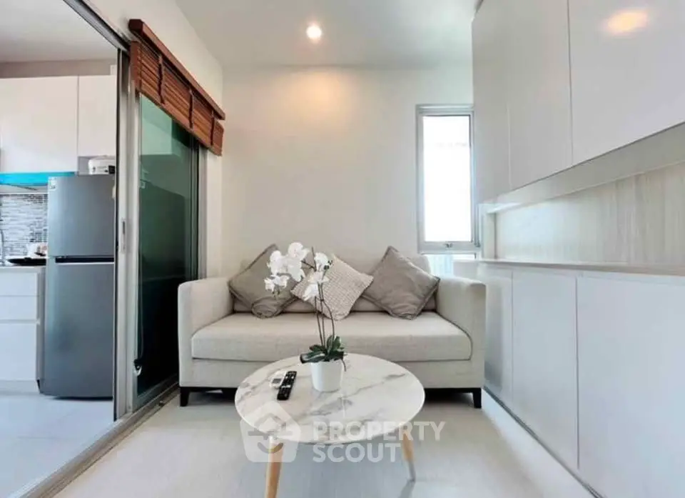 Modern living room with cozy sofa and marble coffee table, adjacent to sleek kitchen area.