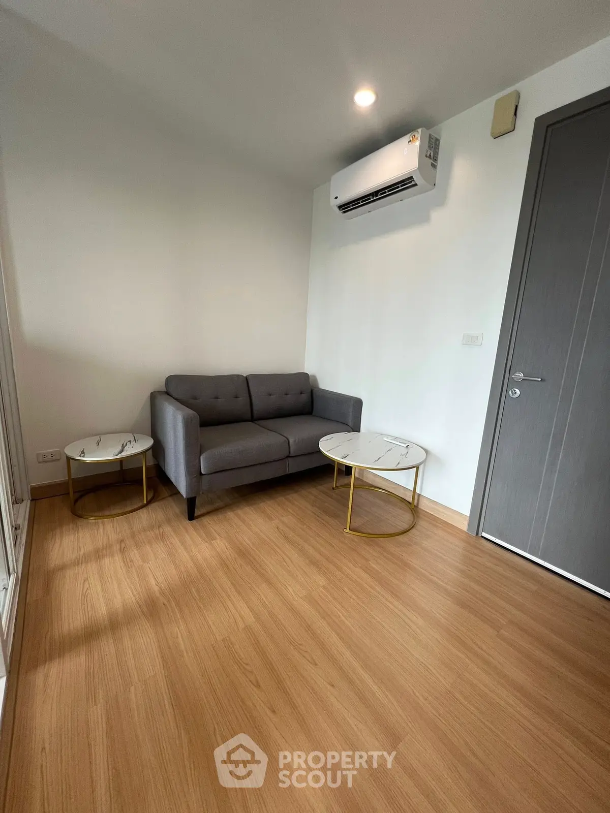 Modern living room with sleek sofa and air conditioning unit, perfect for cozy relaxation.