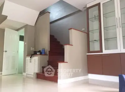 Spacious interior with elegant staircase and built-in display cabinet in modern home.
