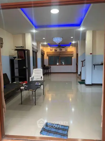 Spacious living room with modern lighting and tiled flooring, perfect for family gatherings.