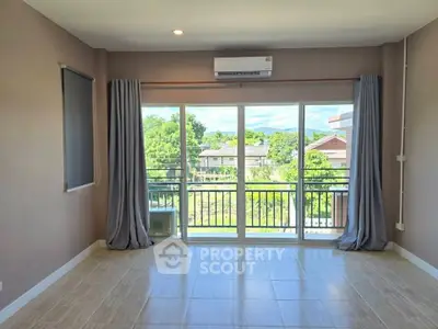 Spacious living room with large windows and balcony offering a serene view, perfect for relaxation.