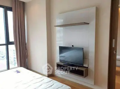 Modern bedroom with mounted TV and large window offering city views.