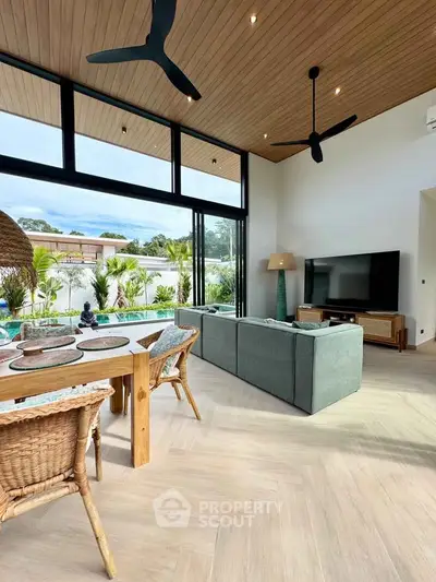 Luxurious living room with pool view, high ceilings, and modern decor in a tropical setting.