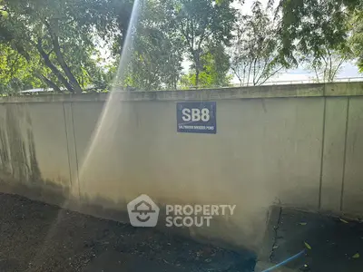 Exterior view of a property boundary wall with trees in the background.