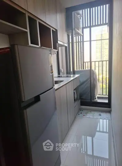 Modern kitchen with sleek appliances and balcony view in urban apartment