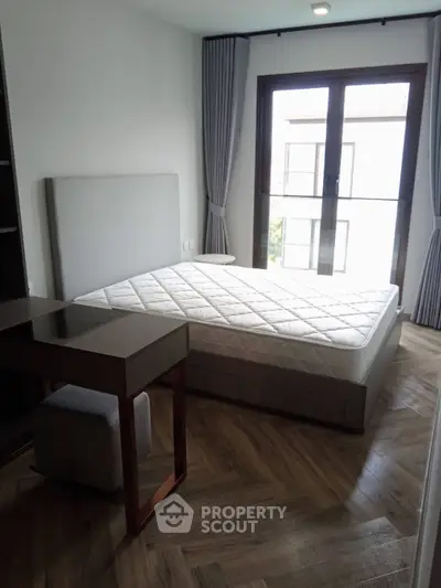 Modern bedroom with stylish parquet flooring and large window for natural light.
