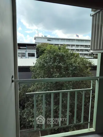 Charming balcony view with lush greenery and cityscape backdrop, perfect for urban living enthusiasts.