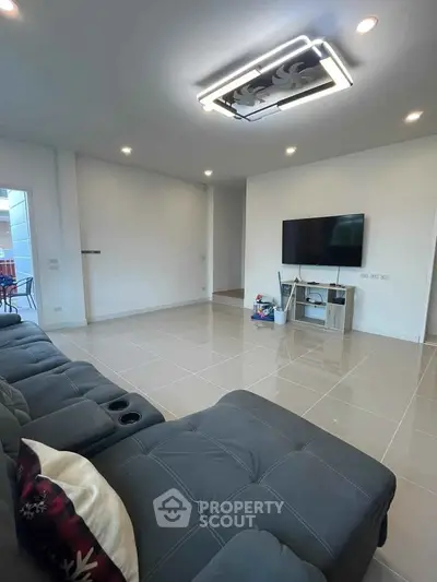 Spacious modern living room with sleek tile flooring and stylish ceiling light fixture.
