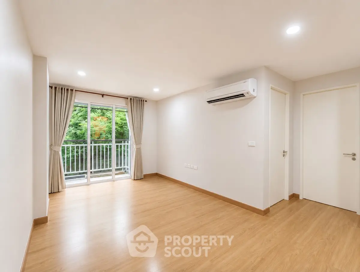 Spacious empty living room with wooden flooring and balcony view