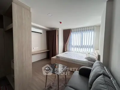Modern bedroom with natural light, featuring a cozy bed, stylish sofa, and sleek wooden furniture.