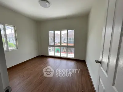 Spacious empty room with large windows and wooden flooring in modern home