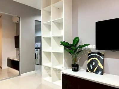 Modern living room with sleek shelving and stylish decor, featuring a washing machine in the background.