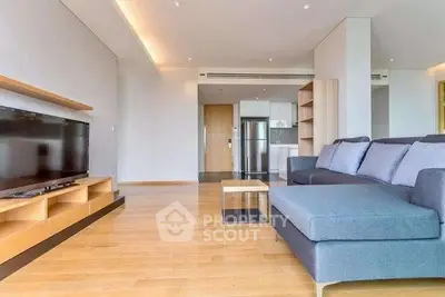 Spacious modern living room with sleek furniture and open kitchen layout.