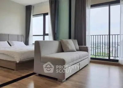 Modern bedroom with large windows and city view, featuring a cozy sofa and elegant decor.
