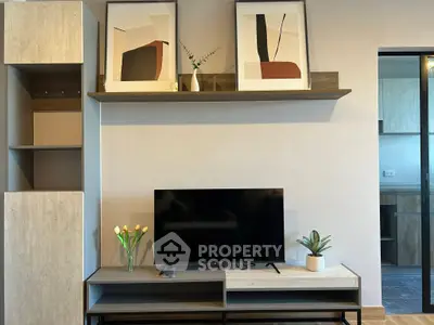 Modern living room with stylish decor and flat-screen TV, featuring contemporary artwork and elegant shelving.