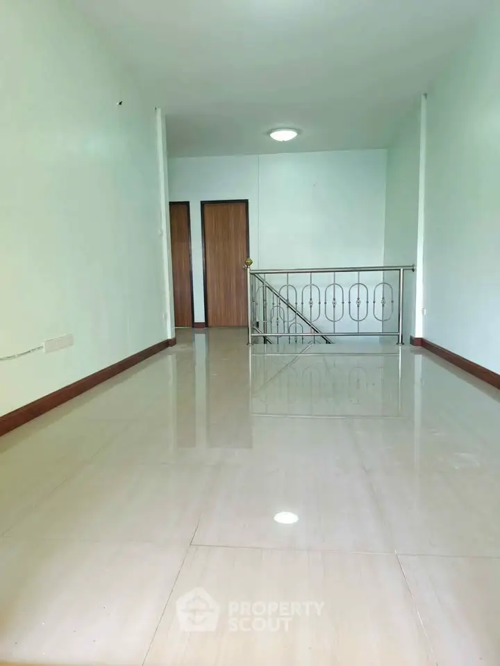 Spacious interior with glossy tiled flooring and modern railing, perfect for versatile living space.
