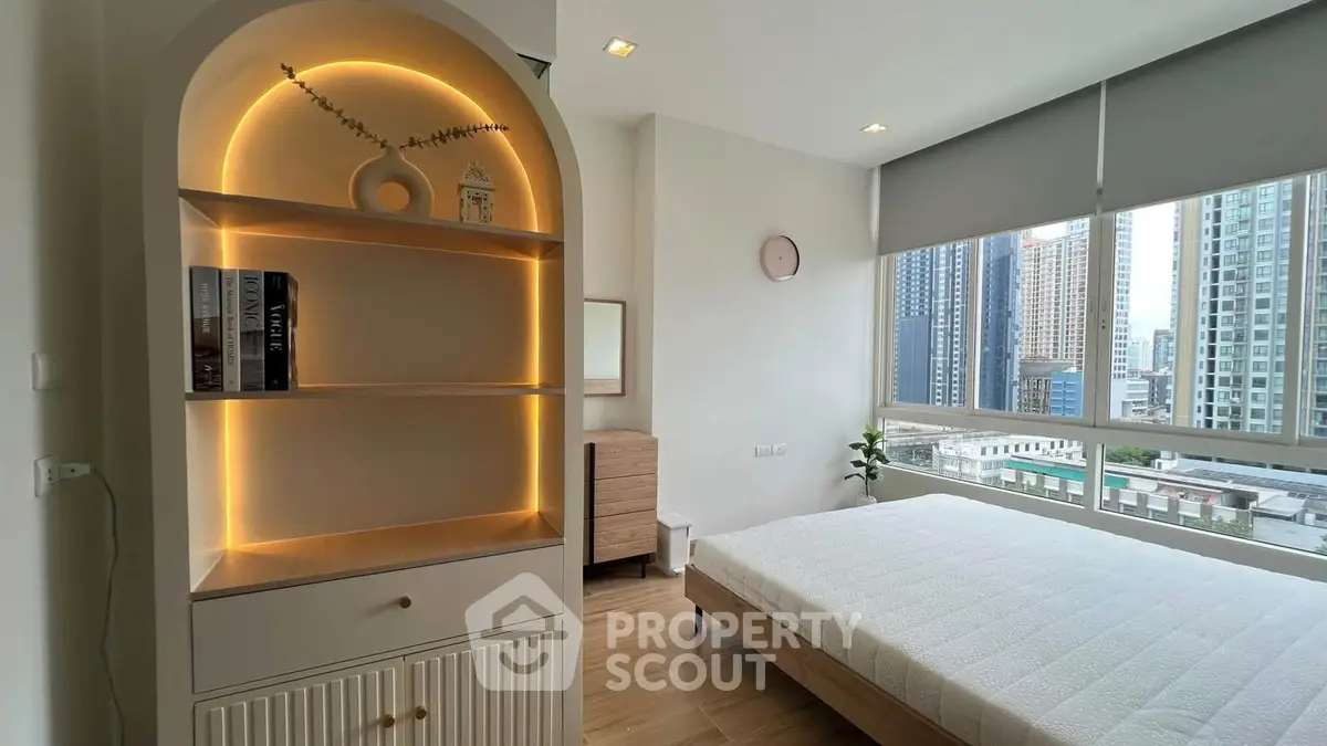 Modern bedroom with city view, featuring stylish built-in shelving and large windows.