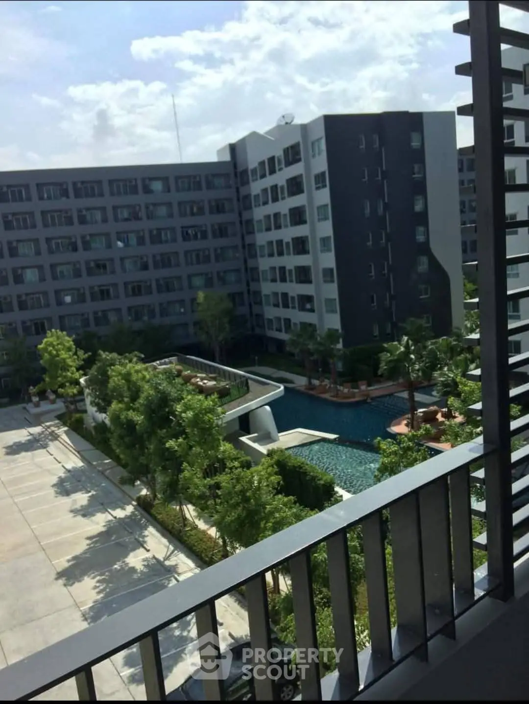 Modern apartment complex with pool and lush greenery view from balcony.