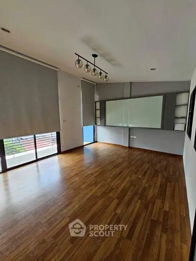 Spacious empty room with wooden flooring and large windows