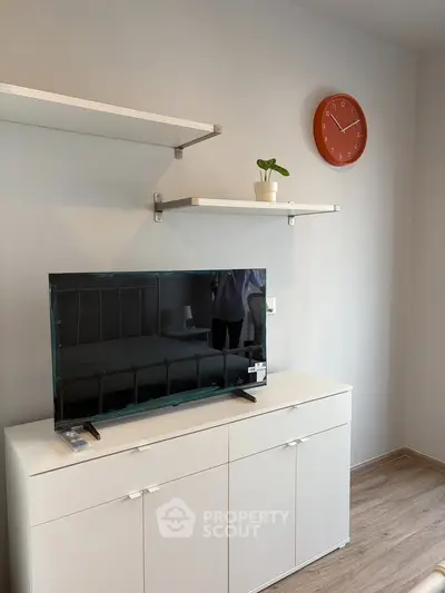 Modern living room with sleek TV stand, floating shelves, and stylish decor.
