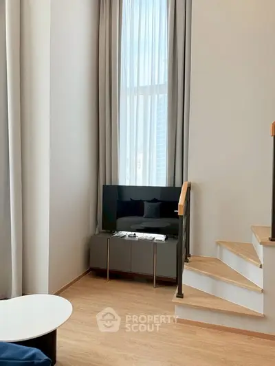 Modern living room with high ceilings and elegant staircase in a stylish apartment.