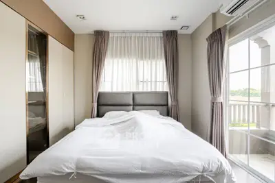 Cozy bedroom with large window and balcony access, featuring modern decor and ample natural light.