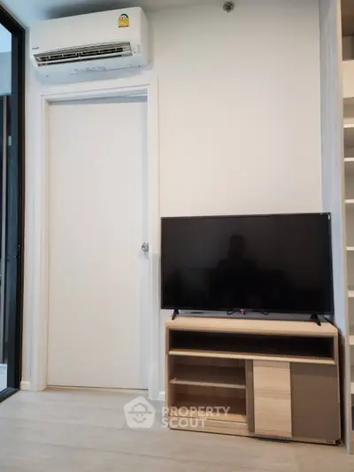 Modern living room with sleek TV setup and air conditioning unit, perfect for cozy entertainment.