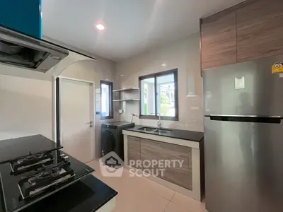 Modern kitchen with gas stove, washing machine, and sleek cabinetry