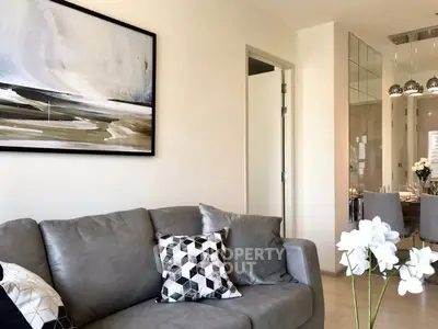 Modern living room with stylish decor and open view to dining area, featuring elegant artwork and cozy seating.