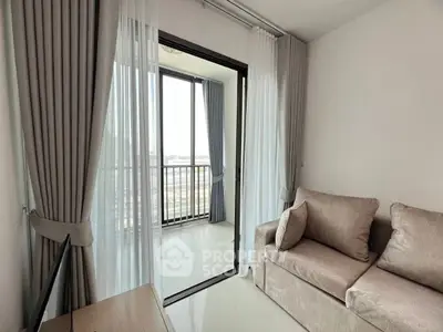 Modern living room with balcony view, featuring elegant curtains and cozy sofa, perfect for relaxation.