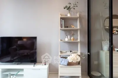 Modern living room with stylish decor and TV unit, featuring a sleek shelving unit and elegant accessories.