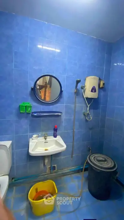 Functional blue-tiled bathroom with sink, mirror, and water heater.
