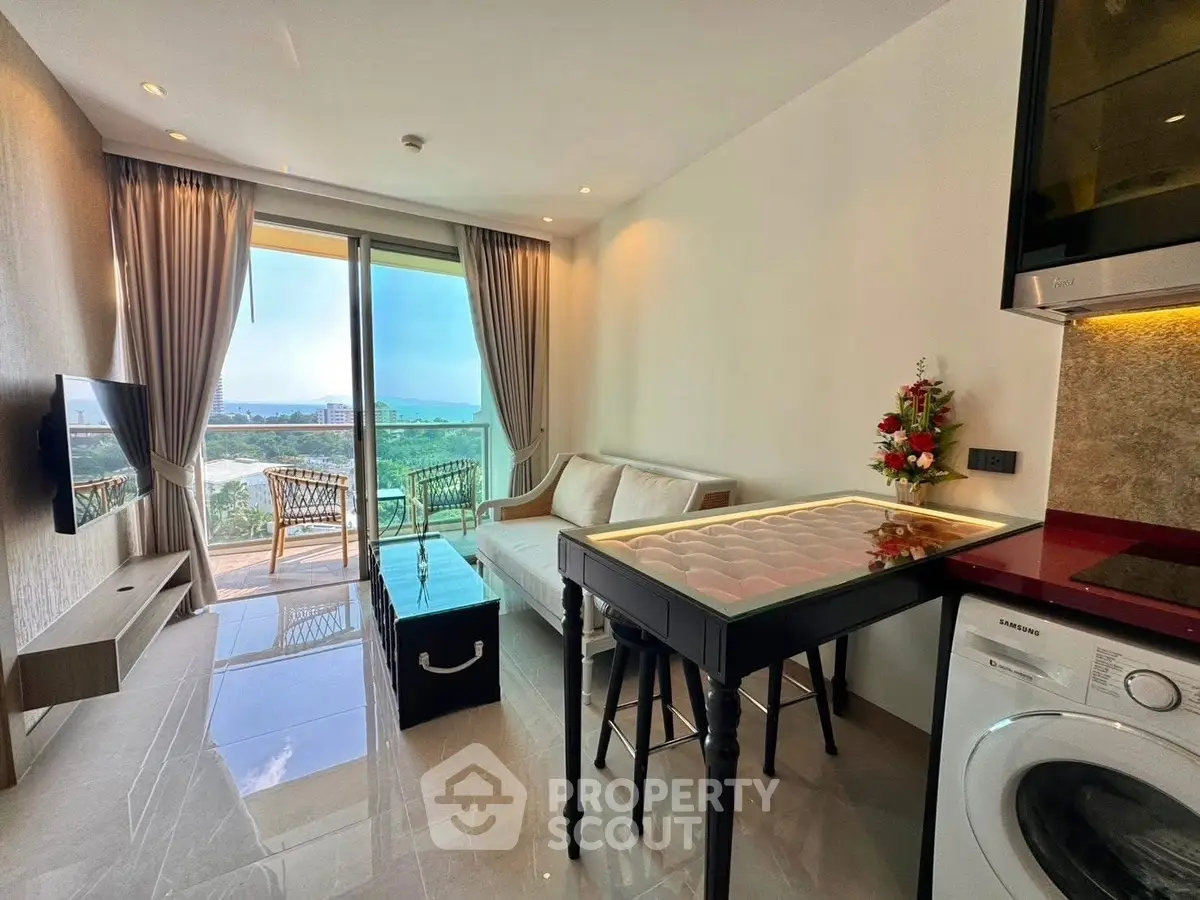 Modern living room with balcony and stunning view, featuring sleek furniture and washing machine.