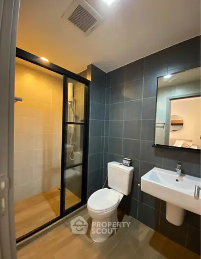 Modern bathroom with sleek design, featuring a glass-enclosed shower and contemporary fixtures.