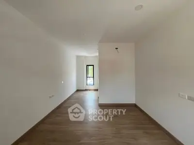 Spacious empty room with wooden flooring and natural light