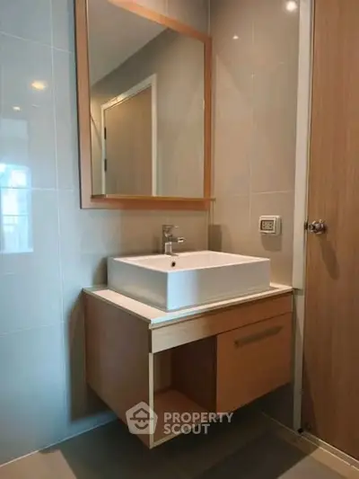 Modern bathroom with sleek vanity and mirror in contemporary design.