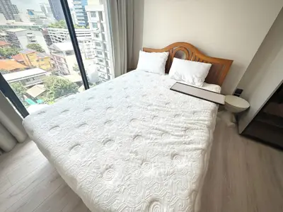 Spacious bedroom with city view and elegant wooden headboard in modern apartment.