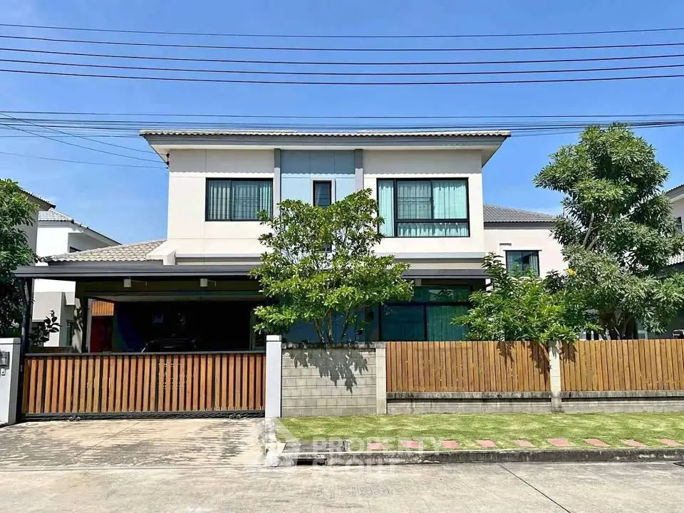 Modern two-story house with a spacious front yard and wooden fence, perfect for family living.