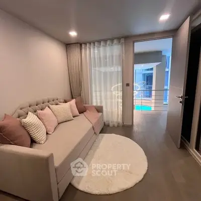 Cozy living room with elegant sofa and soft lighting, overlooking a modern balcony view.