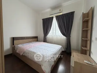 Cozy bedroom with wooden furniture and natural light, perfect for relaxation.