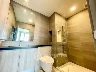 Modern bathroom with glass shower and sleek vanity in contemporary home.