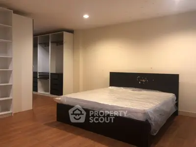 Spacious bedroom with wooden flooring and built-in closet, ideal for modern living.