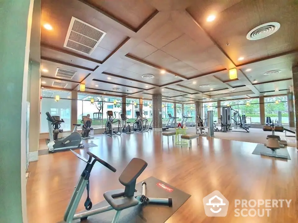 Spacious modern gym with state-of-the-art equipment and large windows for natural light.