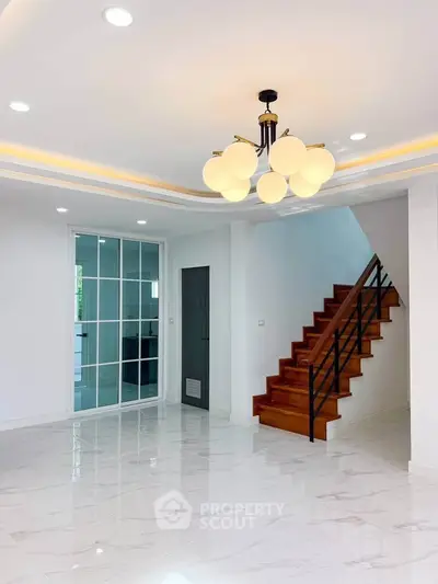 Spacious modern living room with elegant staircase and stylish lighting in a contemporary home.