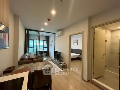 Modern apartment with open living room, dining area, and bedroom view.