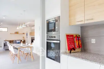 Modern open kitchen with dining area, featuring sleek appliances and stylish lighting.