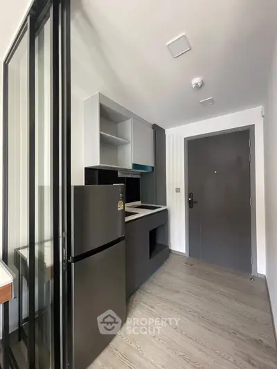 Modern compact kitchen with sleek appliances and stylish cabinetry in a contemporary apartment.