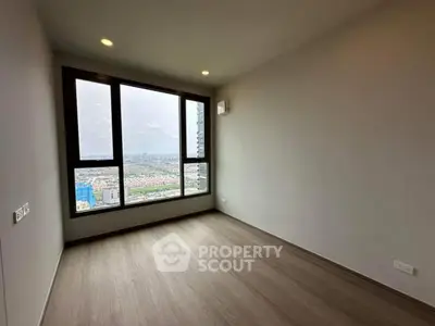 Spacious empty room with large window offering stunning city view