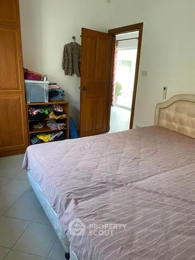 Cozy bedroom with wooden wardrobe and neatly arranged clothes, perfect for comfortable living.