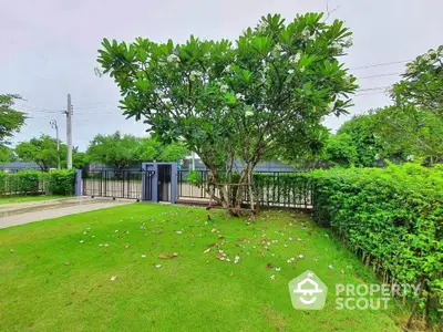 Spacious garden with lush greenery and secure gated entrance